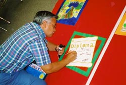 Luis Sámano writing his name on a wall hanging created by students in the Rites of Passage program, 2004.