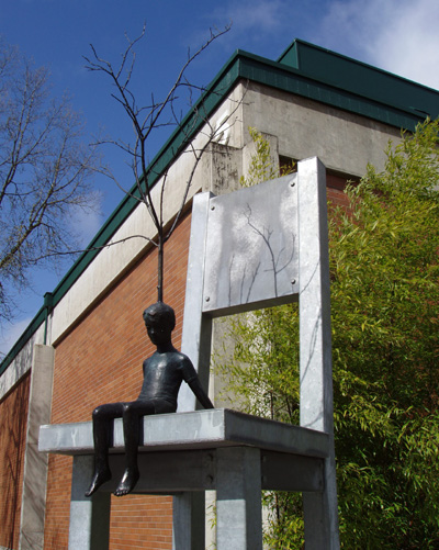 'Conception of Creation' a bronze sculpture by Roger Williams, depicts a small boy with a tree growing out of his head sitting on a giant chair 