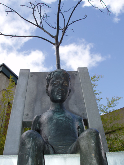 'Conception of Creation' a bronze sculpture by Roger Williams, depicts a small boy with a tree growing out of his head sitting on a giant chair 