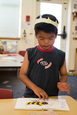 child reading a book, wearing a paper crown