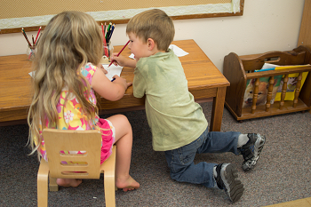 two children sitting and drawing together
