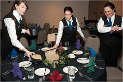 Hospitality students setting tables for event
