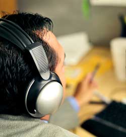 Student wearing headphones looking at computer screen. Photo is meant to show one type of accessible technology, headphones, available.