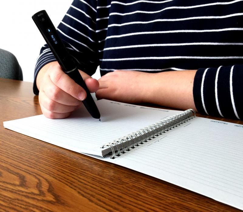 Student using a smartpen, which is a pen with a computer inside that remembers what is written and later will upload it to a computer.