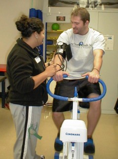 Man on exercise bike getting his blood pressure taken