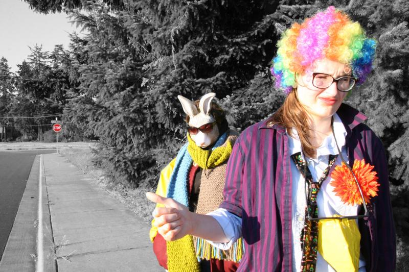 Black and white picture of a colorful woman with a wig and plastic rabbit hitchhiking