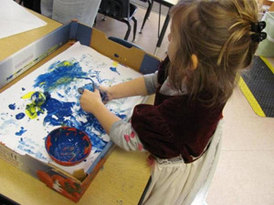 girls with blue finger paint on hands, making picture