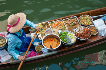 woman paddling canoe with trays of prepared foods