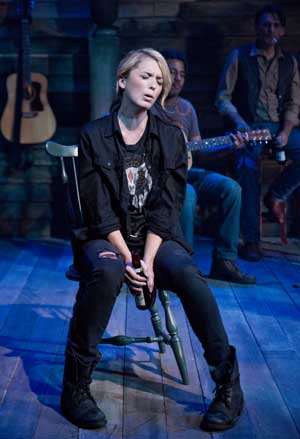 mage of Kacie Sheik, in chair singing, onstage