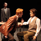 Detective Topolski (David Arnold) watches as Detective Ariel (Aaron Smart) gets rough while interrogating the writer Katurian (Taylor Freeman).