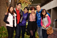students standing together by tree on main campus