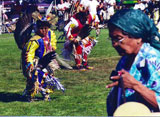 Native American gathering with older woman and dancers