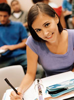 female student smiling for camera while posing taking notes during class