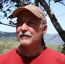 Photo of Roger Ebbage in Costa Rica wearing a baseball cap in a red shirt