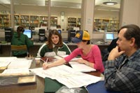 three students sitting at table working on homework