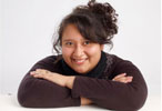 Woman with brown hair and brown sweater smiling at camera